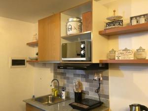 una cucina con lavandino e forno a microonde di La Reina Suite Tuscania Towers a Cagayan de Oro