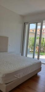 een witte slaapkamer met een bed en een groot raam bij Claudia Apartment Peschiera in Peschiera del Garda