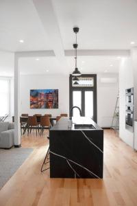 a kitchen with a black island in a living room at Upscale 3-Bedroom Entire Unit in the Trendy Plateau Mont-Royal featuring A Magazine-Worthy Kitchen & Opulent Living Spaces - Apt 1 in Montréal