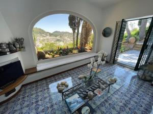 a living room with a large window and a table at Villa La Sosta in Capri