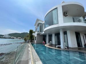a building with a swimming pool next to the water at Nancy Tran Grand Strip Vung Tau Villa 6 in Vung Tau