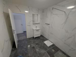 a white bathroom with a sink and a mirror at Apartments Novak in Klenovica