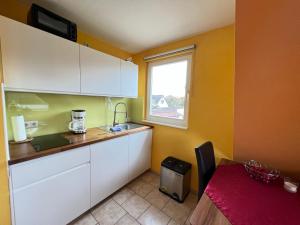 Una cocina con gabinetes blancos y una ventana. en Ferienhaus Brise - Austernperle, en Wieck 5 fotos más