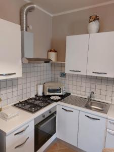 uma cozinha com armários brancos e um forno com placa de fogão em La Torre em Castiglion Fiorentino