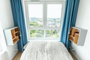 een slaapkamer met blauwe gordijnen en een groot raam bij Studio 71 in Lublin