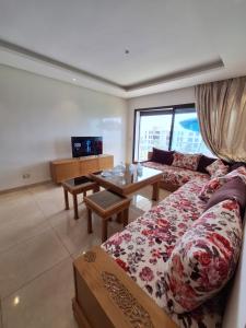 prestigia plage des nation في Sidi Bouqnadel: غرفة معيشة مع أريكة وطاولة