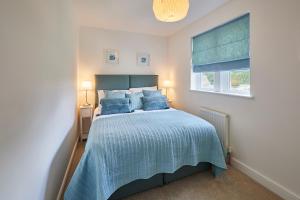 Host & Stay - Clackgill Cottage في Middlesmoor: غرفة نوم بسرير لحاف ازرق ونافذة
