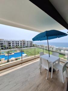 - un balcon avec une table, des chaises et un parasol dans l'établissement prestigia plage des nation, à Sidi Bouqnadel