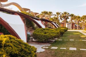 a row of bushes in front of a house with palm trees at Relax in Vieste