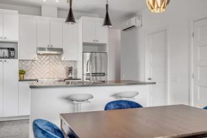 a kitchen with white cabinets and a table with blue chairs at Initial / Artsy / Centre ville de Quebec in Quebec City