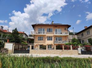 een groot huis met een hek ervoor bij Family Hotel Velevi in Velingrad