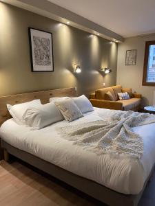 a bedroom with a large bed and a couch at Cit'Hôtel le Welcome in Moutiers