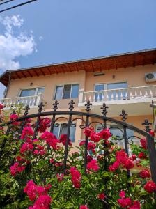 a fence with pink flowers in front of a building at Family Hotel Velevi in Velingrad