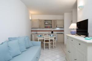 a living room with a blue couch and a kitchen at Harry's House by Wonderful Italy in Porto Rotondo