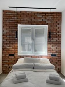 a bed in front of a brick wall with a window at Apartament LOFT in Ostróda
