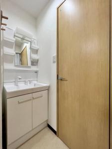 a bathroom with a sink and a wooden door at RAKUTO通天閣301 特價2室1厅,日本橋難波心斎橋1站, 車站3分,緊鄰通天閣, 直達關西機場大阪城USJ京都. in Osaka