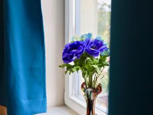 eine Vase mit blauen Blumen im Fenster in der Unterkunft Residenz am Dresdner Stadtwald in Dresden