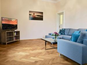 ein Wohnzimmer mit einem blauen Sofa und einem TV in der Unterkunft Residenz am Dresdner Stadtwald in Dresden