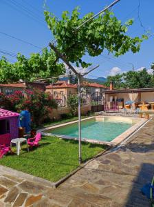 - une piscine dans une cour avec des chaises roses et un arbre dans l'établissement Family Hotel Velevi, à Velingrad