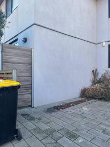 uma lata de lixo ao lado de um edifício branco em Cosy Studio with Courtyard in Vibrant Fitzroy! em Melbourne