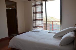 a bedroom with a white bed with a large window at Zan-Seyoum Hotel - Lalibela in Lalibela