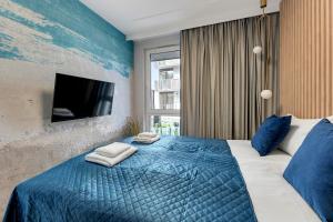 a bedroom with a blue bed and a tv at GRANO FLATS Sobieszewo - Baltic Line in Gdańsk
