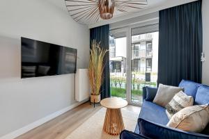 a living room with a blue couch and a tv at GRANO FLATS Sobieszewo - Baltic Line in Gdańsk
