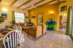 ein Wohnzimmer mit gelben Wänden sowie einem Tisch und Stühlen in der Unterkunft 26 Casa Chibi Chibi in Kralendijk