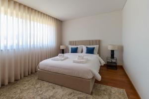 1 dormitorio con 1 cama grande con almohadas azules en Viana's Heart - Spacious Modern Ap. Near City Center, en Viana do Castelo