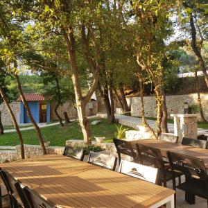 a wooden table and chairs in a yard with trees at Green Hill Apartments in Ulcinj