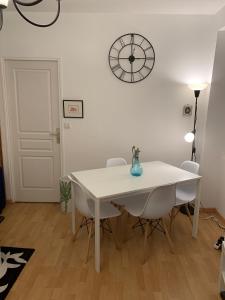 une table et des chaises blanches dans une pièce avec une horloge sur le mur dans l'établissement Biarritz centre bel Apt 2 pièces rue calme, à Biarritz