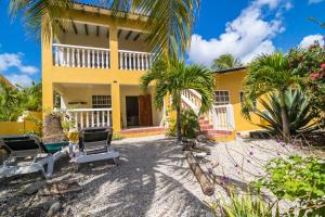 une maison jaune avec deux chaises et des palmiers dans l'établissement 28B Casa Kokolishi, à Kralendijk