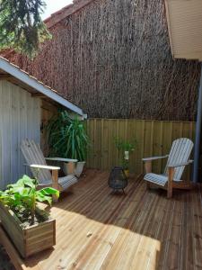 2 Stühle und ein Tisch auf einer Holzterrasse in der Unterkunft Maison avec piscine in Castelnau-de-Médoc