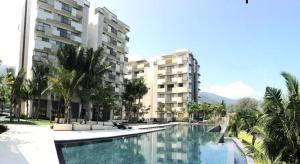a large swimming pool in front of a building at By The Sea Luxury Beachfront Resort 223 in Batu Ferringhi