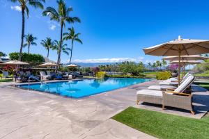 a swimming pool with lounge chairs and an umbrella at Kolea Kai 16D in Waikoloa
