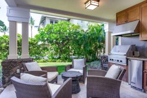 a patio with chairs and a stove and a grill at Kolea Kai 16D in Waikoloa