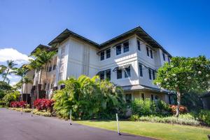 duży biały dom z drzewami przed nim w obiekcie Kolea Kai 16D w mieście Waikoloa