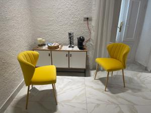 2 chaises jaunes et une table dans une pièce dans l'établissement Ischia suite, à Termini Imerese