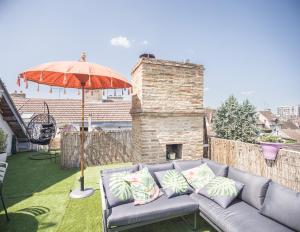 un divano grigio con cuscini sotto un ombrello di Le Rooftop - vue Cathédrale - Climatisation a Troyes