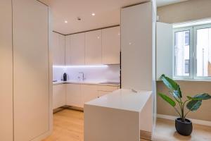 une cuisine avec des armoires blanches et une plante en pot dans l'établissement Liberdade Elegance W/Rooftop Pool by LovelyStay, à Lisbonne