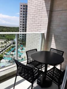 a black table and chairs on a balcony with a pool at SALINAS EXCLUSIVE RESORT in Salinópolis