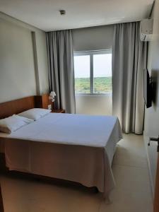 a bedroom with a large bed and a window at SALINAS EXCLUSIVE RESORT in Salinópolis