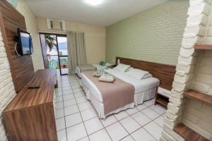 a bedroom with a bed and a television in it at Portogalo Suite Hotel in Angra dos Reis