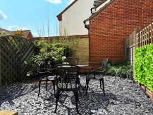 a patio with four chairs and a table and a fence at Layla's Place in Hertfordshire in Chesfield