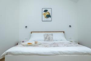 a white bedroom with a bed with a tray on it at Apartments Seafront in Pupnat