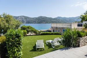 a yard with two lawn chairs and a view of the water at Apartments Seafront in Pupnat