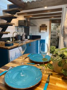 - une table en bois avec 2 assiettes bleues et des verres à vin dans l'établissement La Tiny Blue - maison insolite pour 2 - sans Tv, à Saint-Aignan