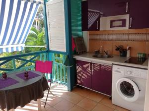 a kitchen with a table and a washing machine at Studio Mahogany in Sainte-Anne