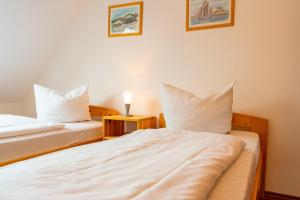 - une chambre avec 2 lits dotés de draps et d'oreillers blancs dans l'établissement Feriendomizil Wiesenhaus, à Zingst