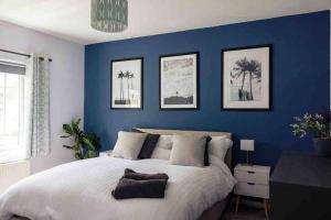 a bedroom with a blue wall with a large bed at Braunton Beach Boutique in Wrafton